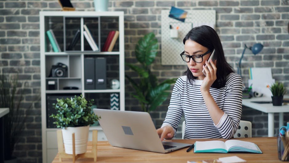 A woman working at her desk with laptop and phone, showcasing a modern office environment.