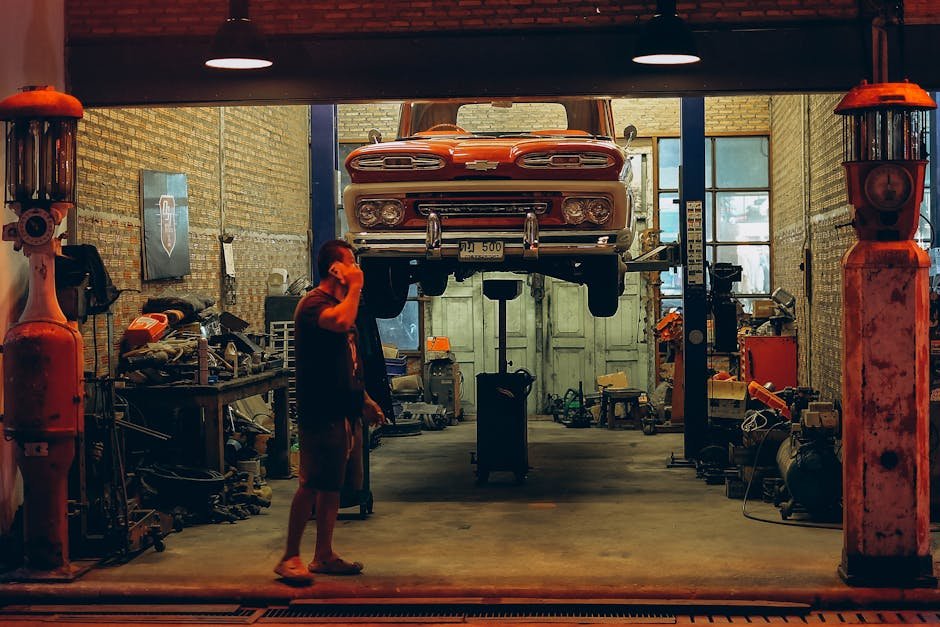 A red vintage truck is lifted in a Bangkok garage. Industrial setting with nostalgic automotive elements.