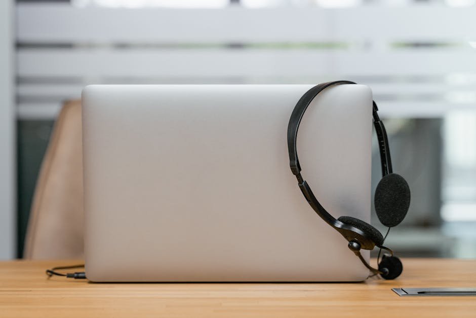 Sleek laptop and a headset on a desk, perfect for remote work or online conferences.