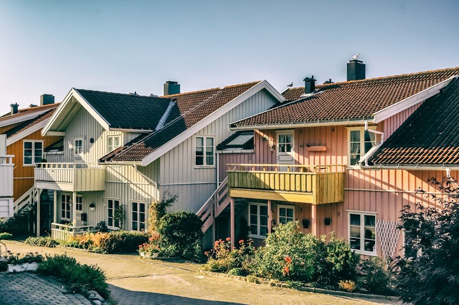 Beautiful pastel-colored Scandinavian houses with vibrant gardens in a sunny residential area.