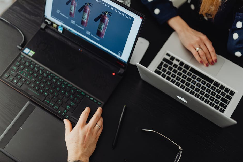 A high-angle view of two people working on laptops at an office desk, showcasing teamwork and technology.