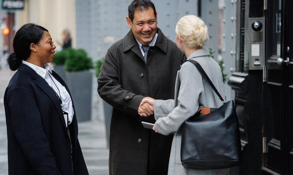 Diverse group of business professionals meeting and shaking hands outdoors in a city setting.