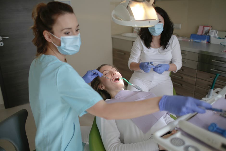 Female dentist and assistant performing a routine dental check-up on a patient in a modern clinic.