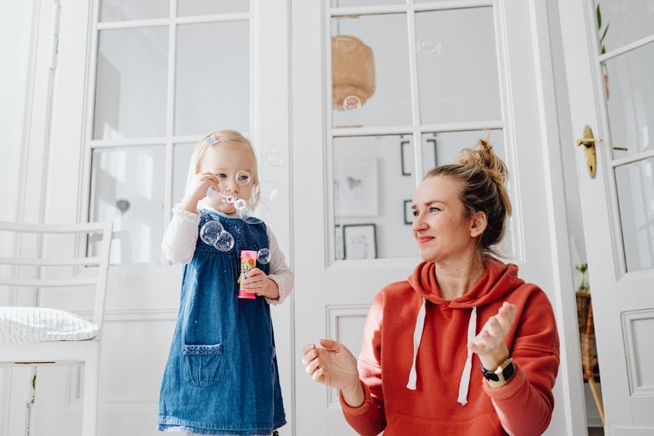 A joyful moment of a mother and daughter playing with bubbles indoors.