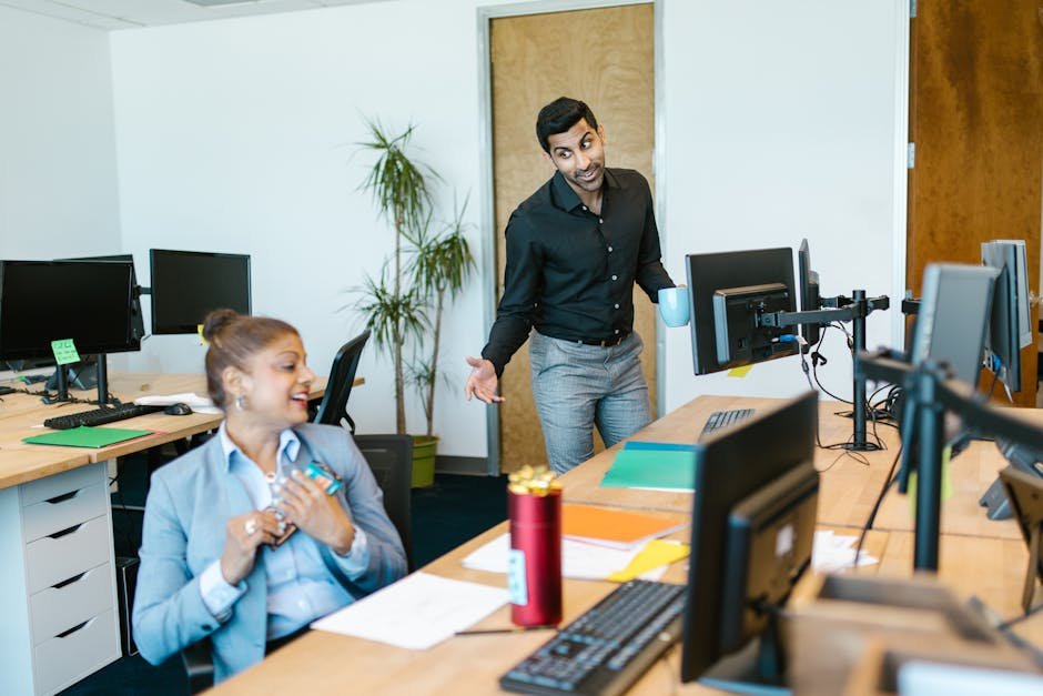Two colleagues engaging in a cheerful conversation in a modern office setting.