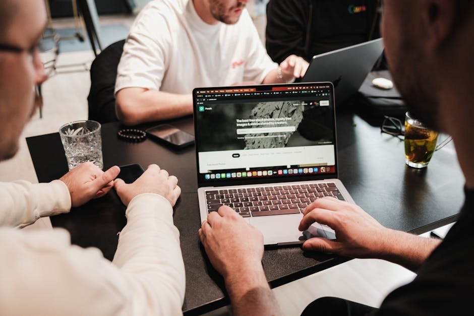 Group of colleagues collaborating on laptops at a modern office table.