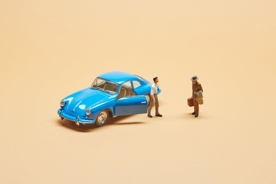 A miniature blue vintage car with two figurines on a beige background, perfect for modeling or creative projects.