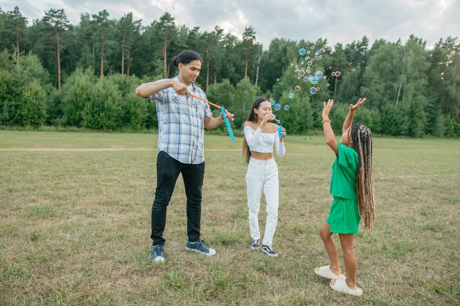 Modern family playing with soap bubbles outdoors in park, enjoying laughter and joy.
